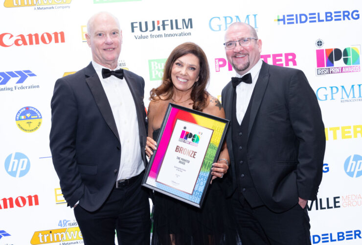 two men and 1 female smiling holding a print award