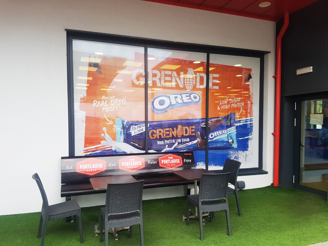 Outdoor signage for a shop for grenade protein bar in orange and blue